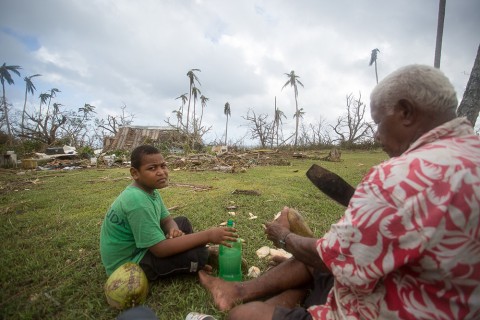 Friends in Ciqomi sitting near the rubble that was their house.